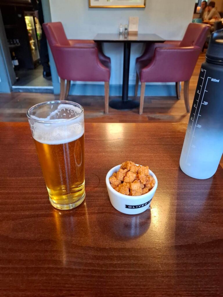 Pint of beer and a bowl of nuts on a pub table