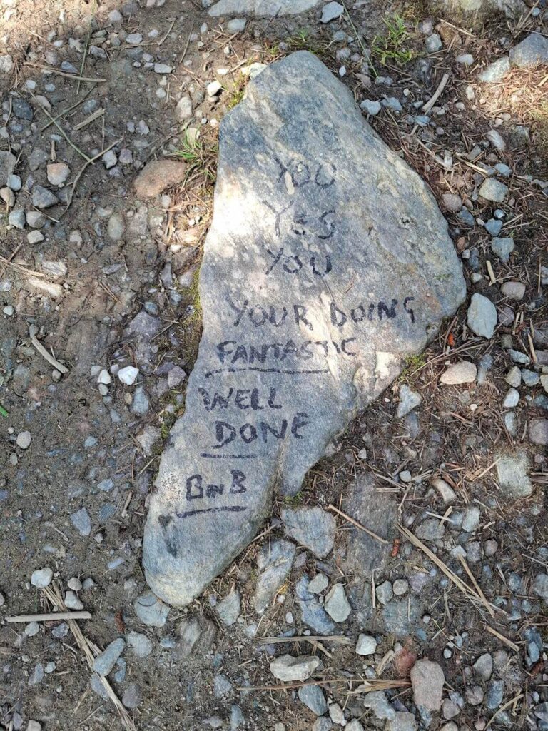 Rock beside the path with a hand‑painted encouragement message